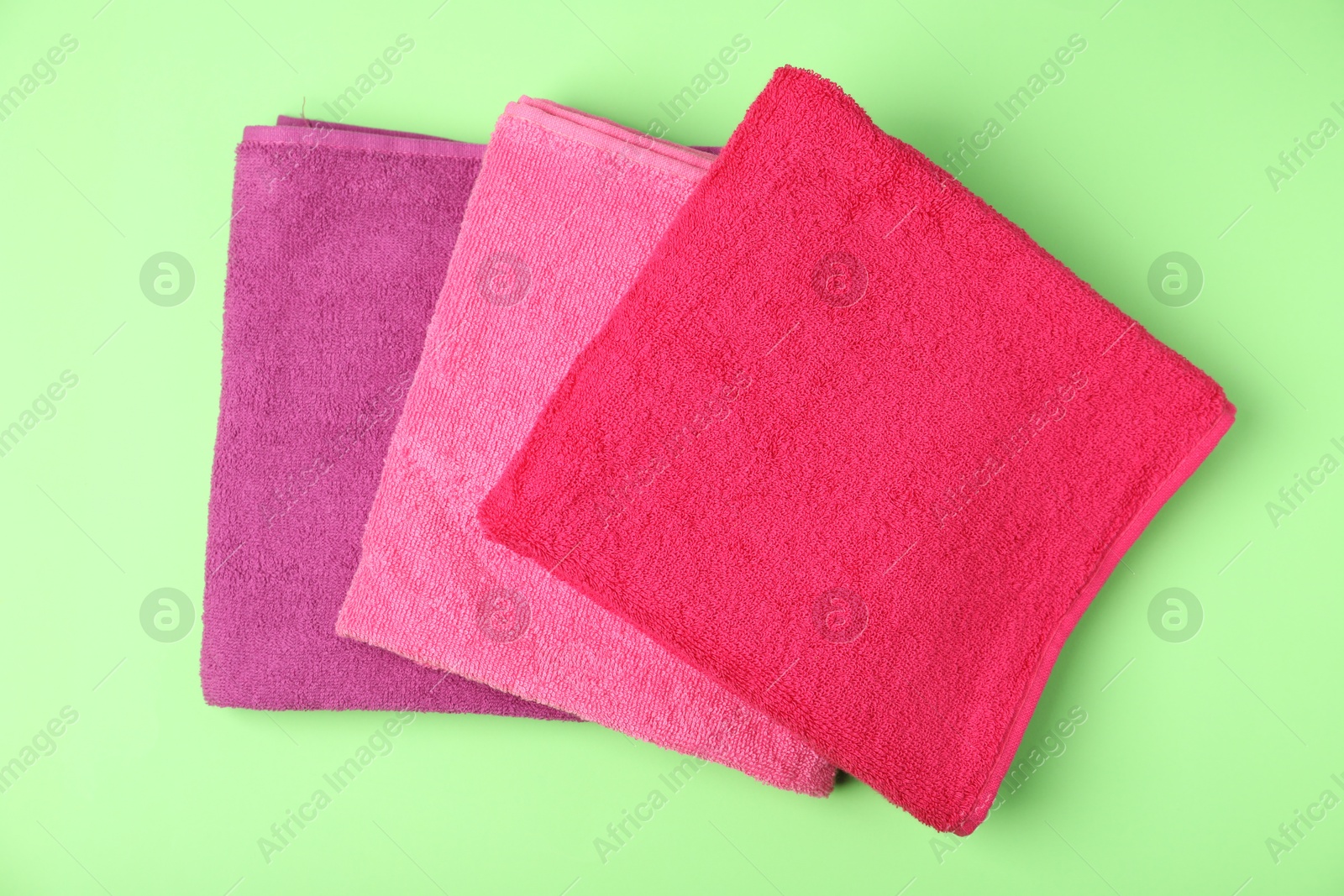 Photo of Bright terry towels on green background, top view