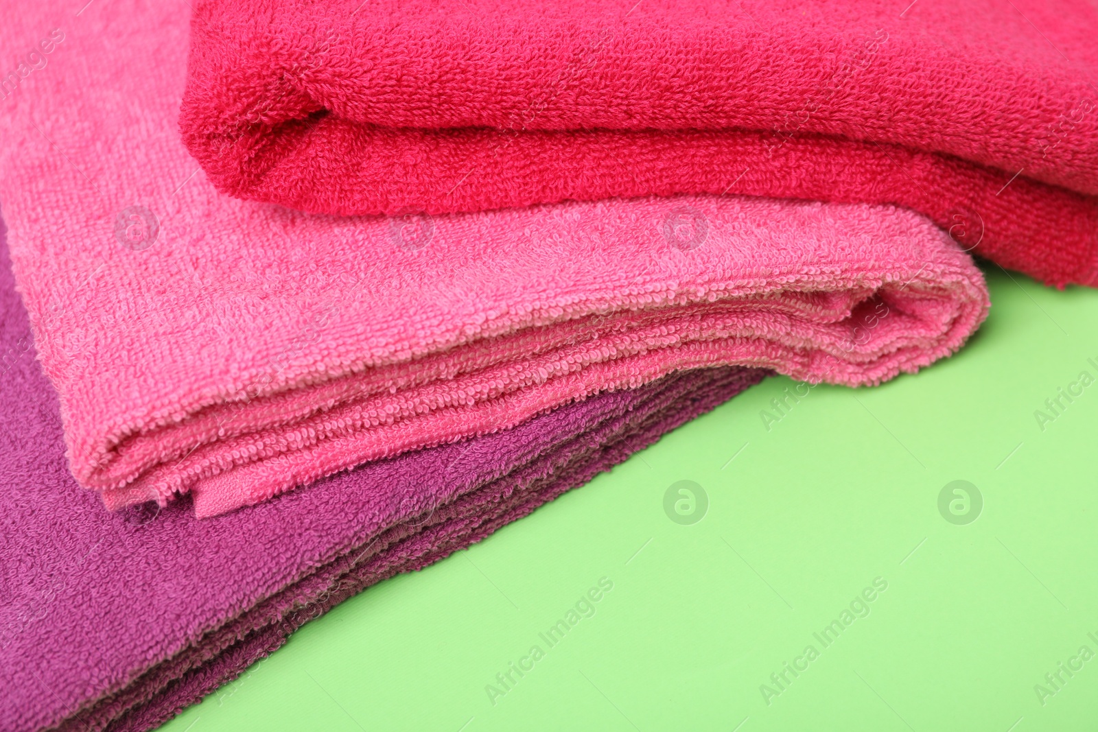 Photo of Bright terry towels on green background, closeup