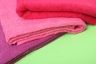 Photo of Bright terry towels on green background, closeup