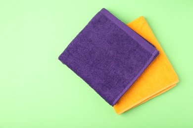 Photo of Bright terry towels on green background, top view. Space for text