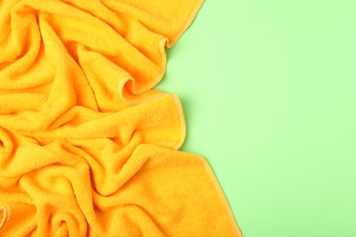 Photo of Yellow terry towel on green background, top view. Space for text