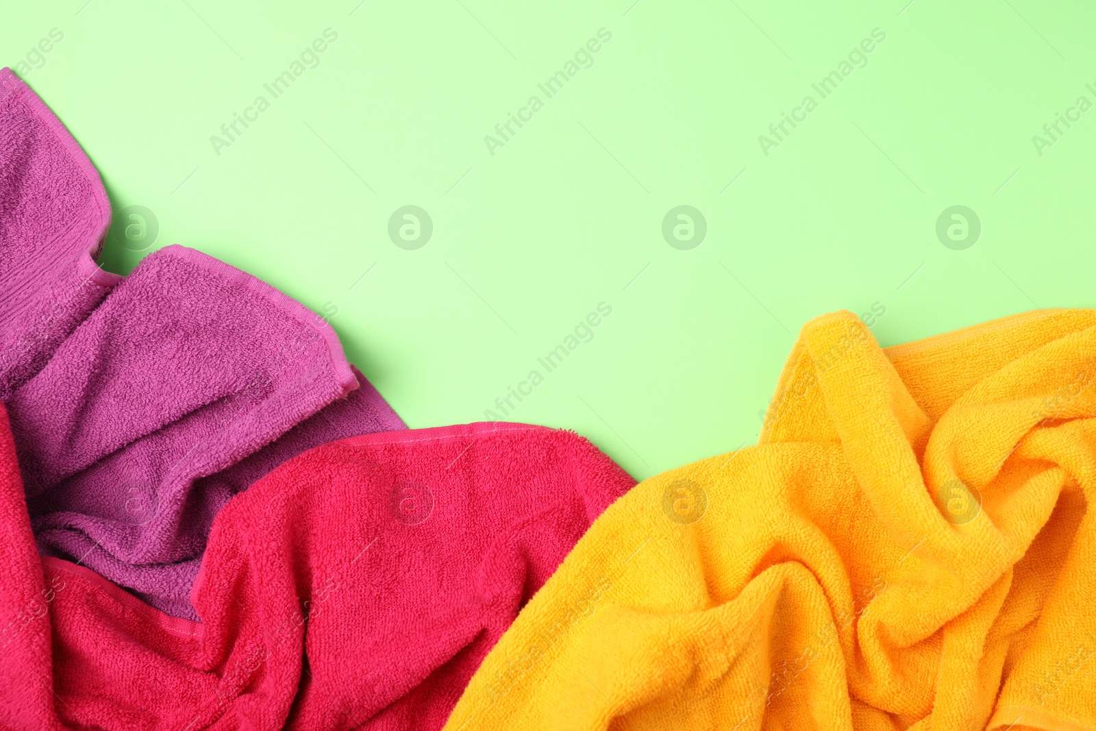 Photo of Bright terry towels on green background, flat lay. Space for text