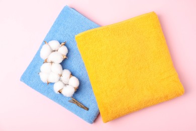 Photo of Bright terry towels and cotton flowers on pink background, flat lay