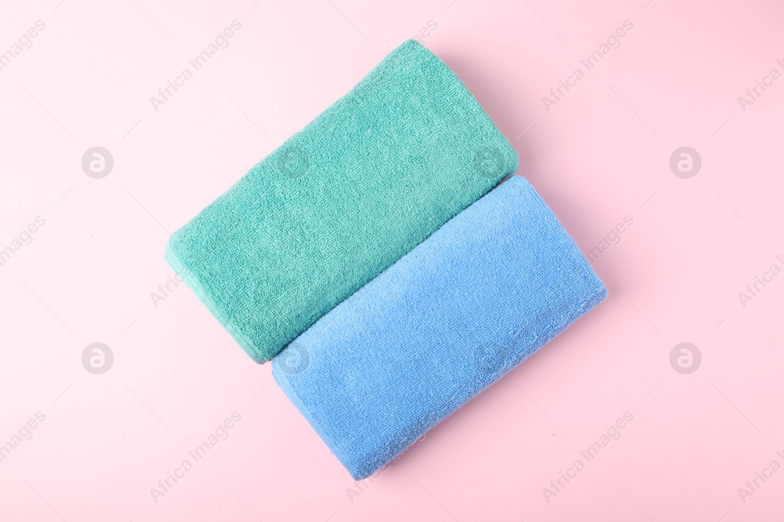 Photo of Bright terry towels on pink background, top view