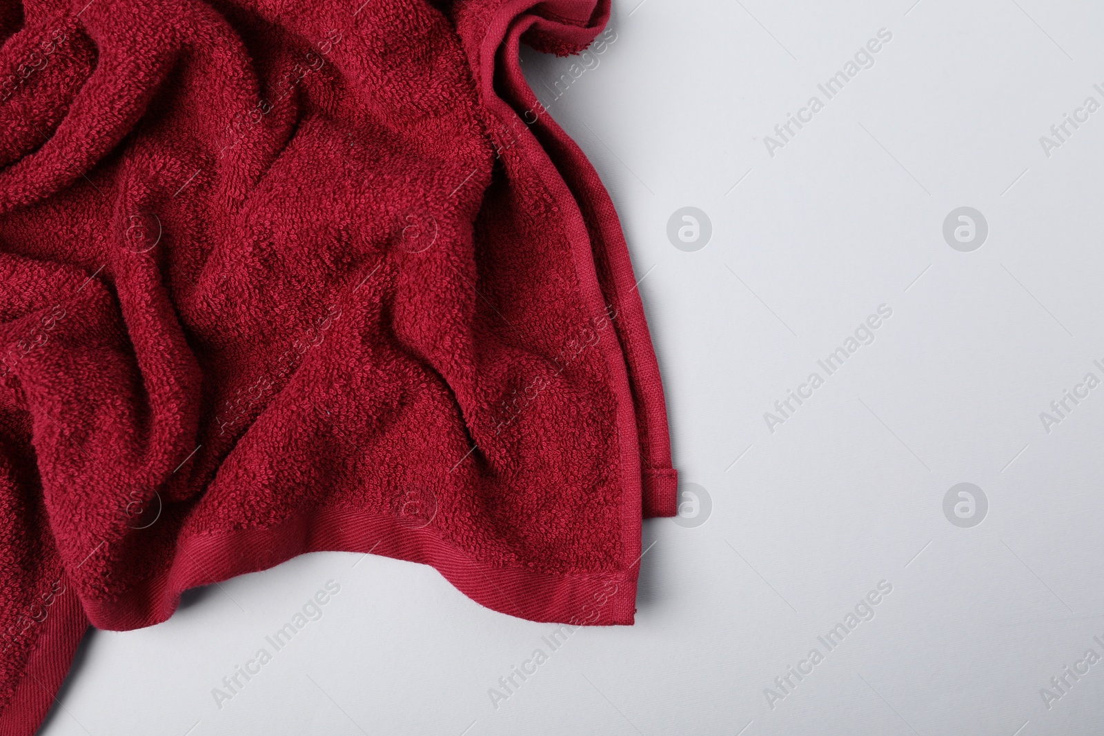 Photo of Red terry towel on light grey background, top view. Space for text