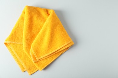 Photo of Yellow terry towel on light grey background, top view. Space for text