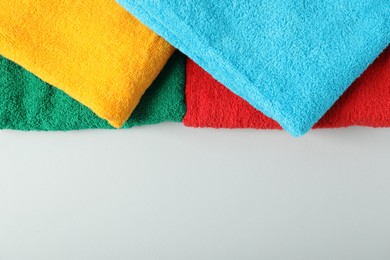 Photo of Bright terry towels on light grey background, top view. Space for text