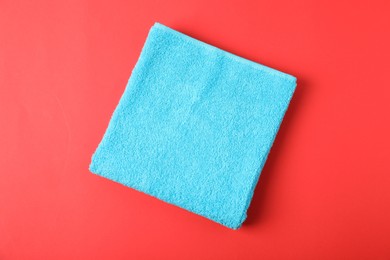 Photo of Light blue terry towel on red background, top view