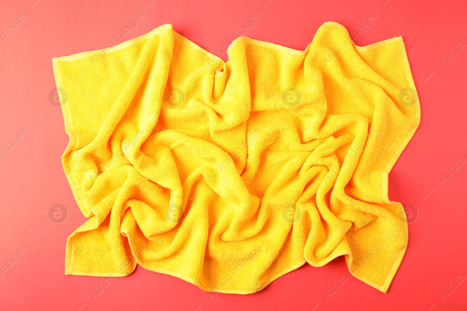 Yellow terry towel on red background, top view Photo of Yellow terry towel on red background, top view