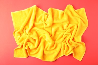 Photo of Yellow terry towel on red background, top view