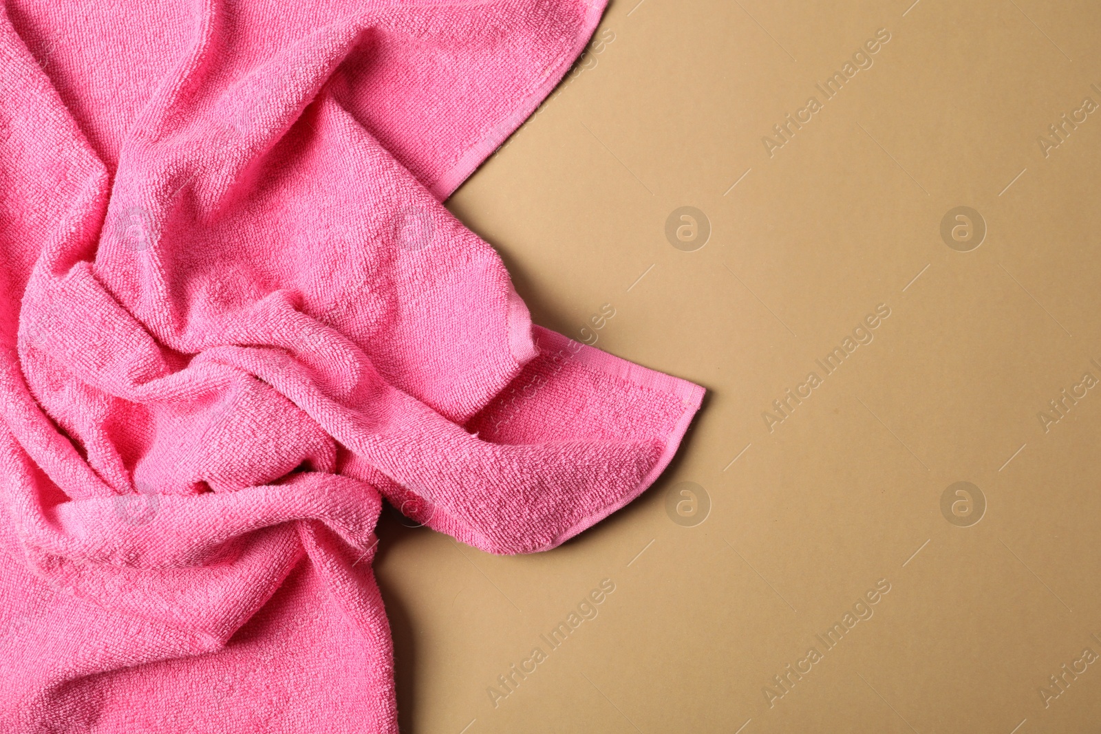 Photo of Pink terry towel on beige background, top view. Space for text