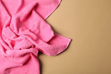 Photo of Pink terry towel on beige background, top view. Space for text