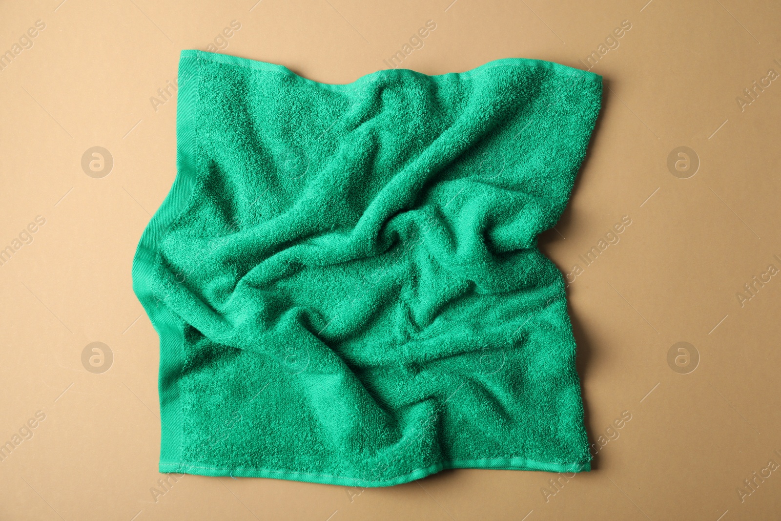 Photo of Green terry towel on beige background, top view
