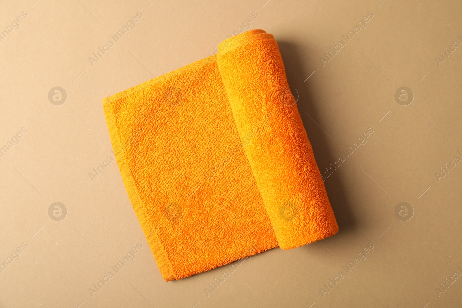Photo of Orange terry towel on beige background, top view