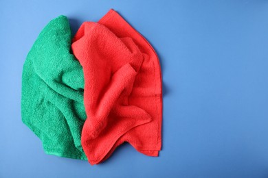 Photo of Bright terry towels on blue background, above view. Space for text