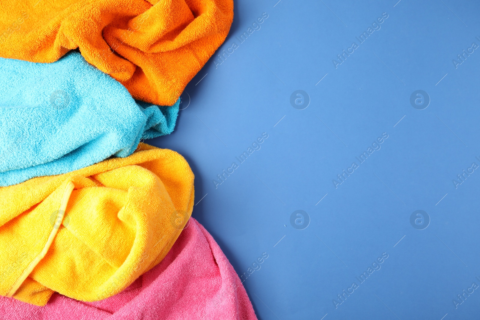 Photo of Bright terry towels on blue background, top view. Space for text