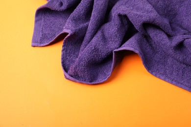 Photo of Purple terry towel on orange background, top view. Space for text