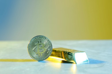 Photo of Bitcoin and gold bar on table in bright lights, closeup with space for text