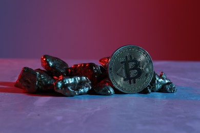 Photo of Bitcoin and gold nuggets on table in bright light