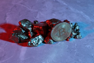 Photo of Bitcoin and gold nuggets on table in bright light