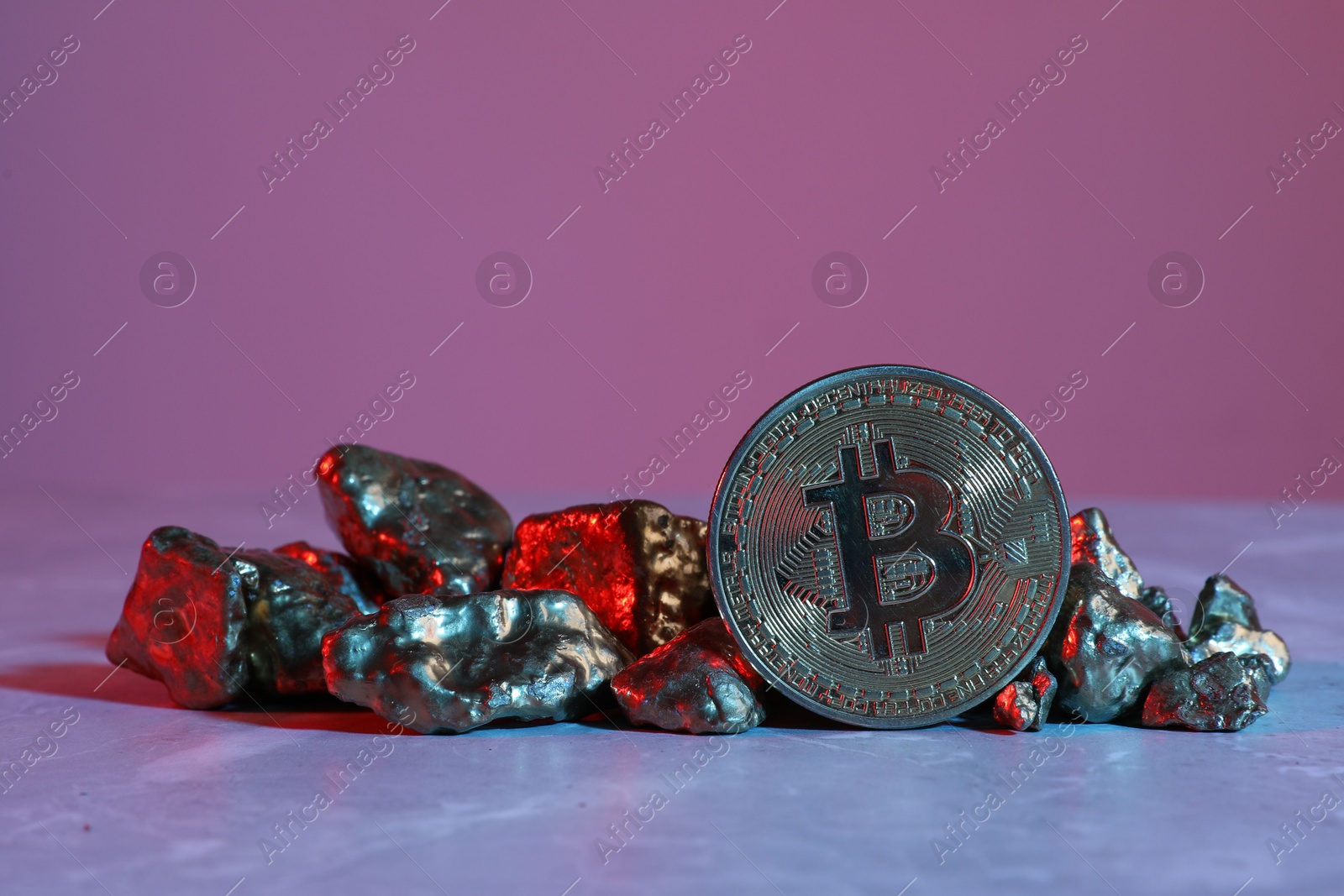 Photo of Bitcoin and gold nuggets on table in bright light
