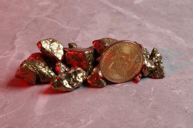 Photo of Bitcoin and gold nuggets on table in red light