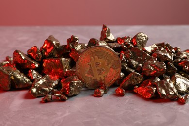 Photo of Bitcoin and gold nuggets on table in red light