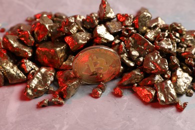 Photo of Bitcoin and gold nuggets on table in red light