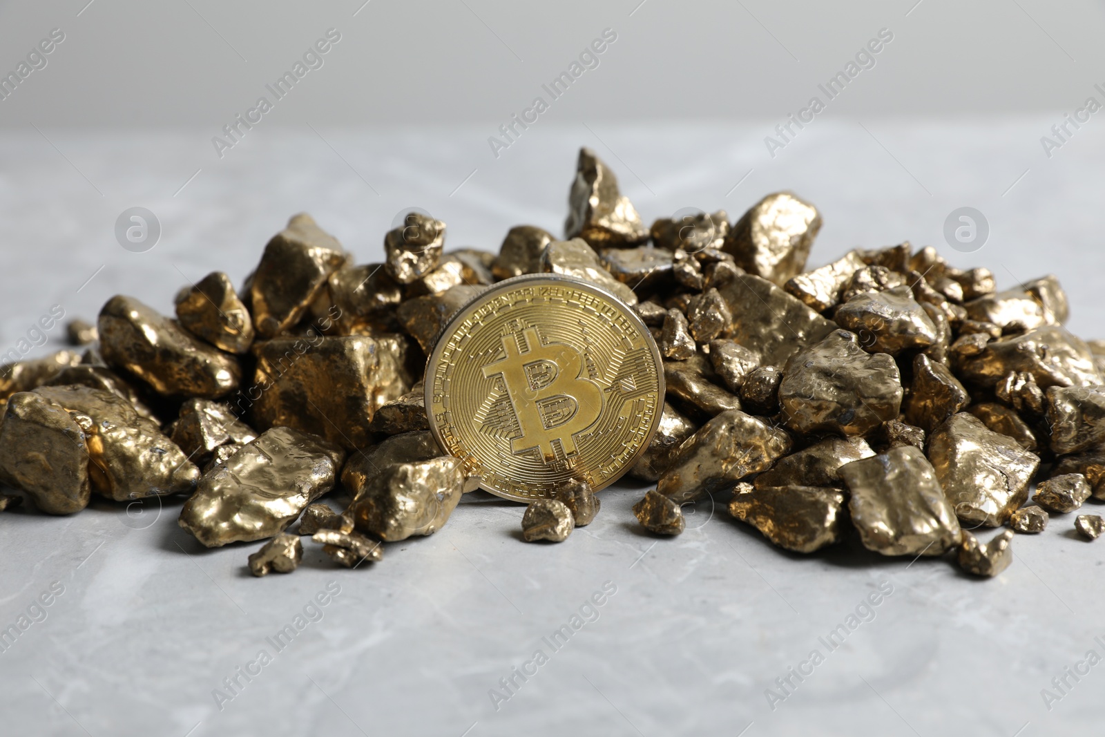 Photo of Bitcoin and gold nuggets on light table, closeup