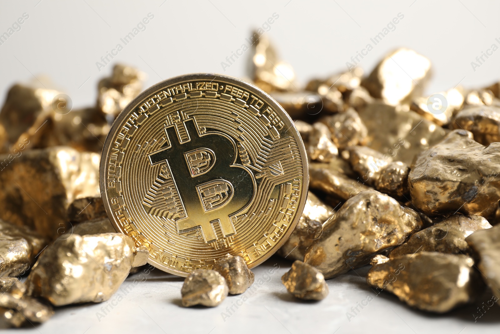 Photo of Bitcoin and gold nuggets on light table, closeup