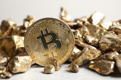 Photo of Bitcoin and gold nuggets on light table, closeup