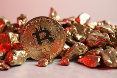 Photo of Bitcoin and gold nuggets on table in red light, closeup