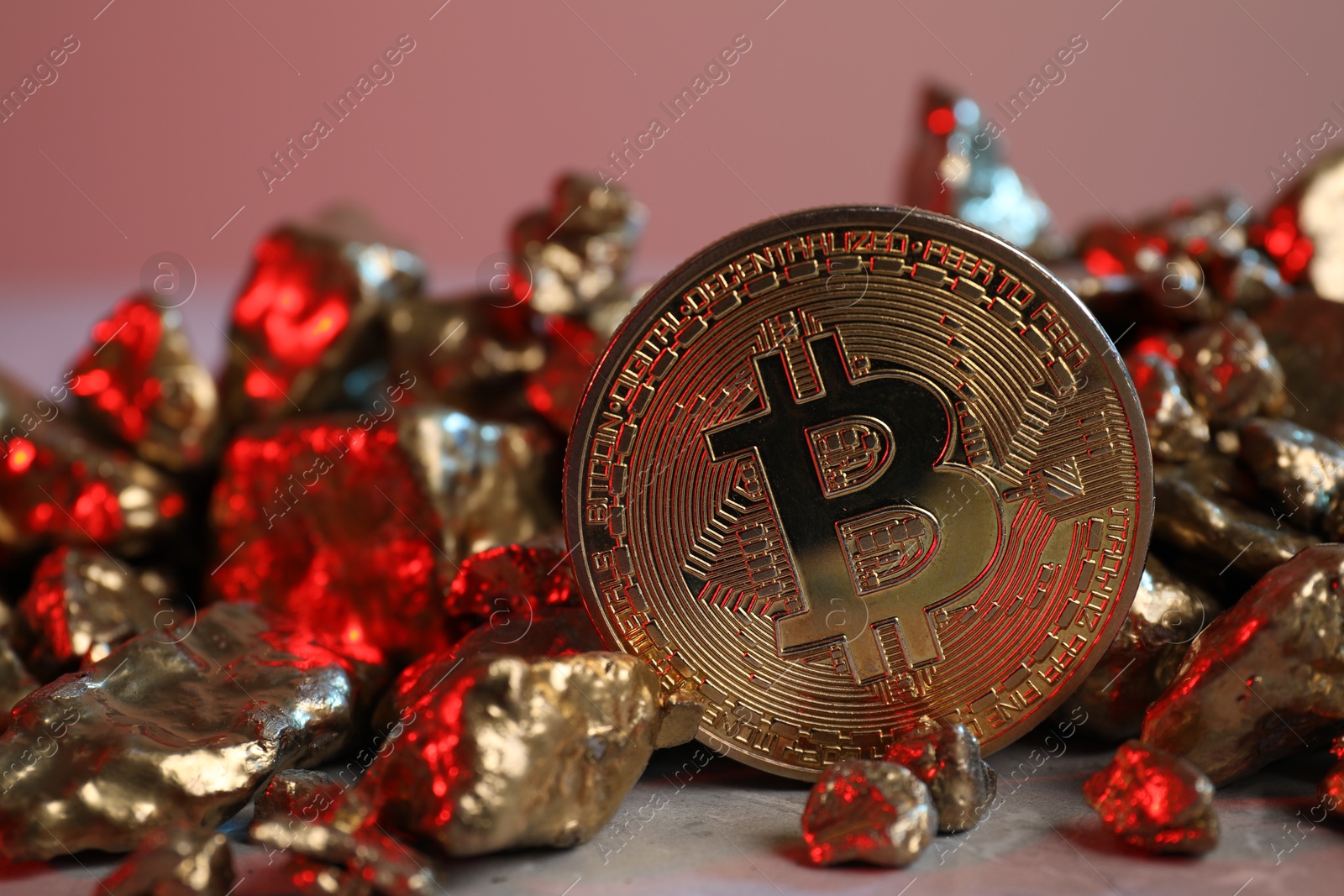 Photo of Bitcoin and gold nuggets on table in red light, closeup