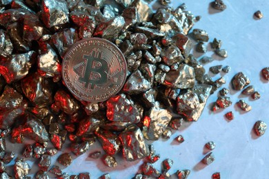 Photo of Bitcoin and gold nuggets on table in red light, flat lay