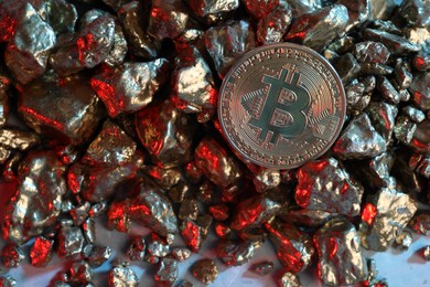 Photo of Bitcoin and gold nuggets on table in red light, flat lay