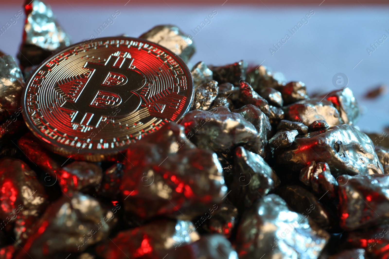 Photo of Bitcoin and gold nuggets on table in red light, closeup