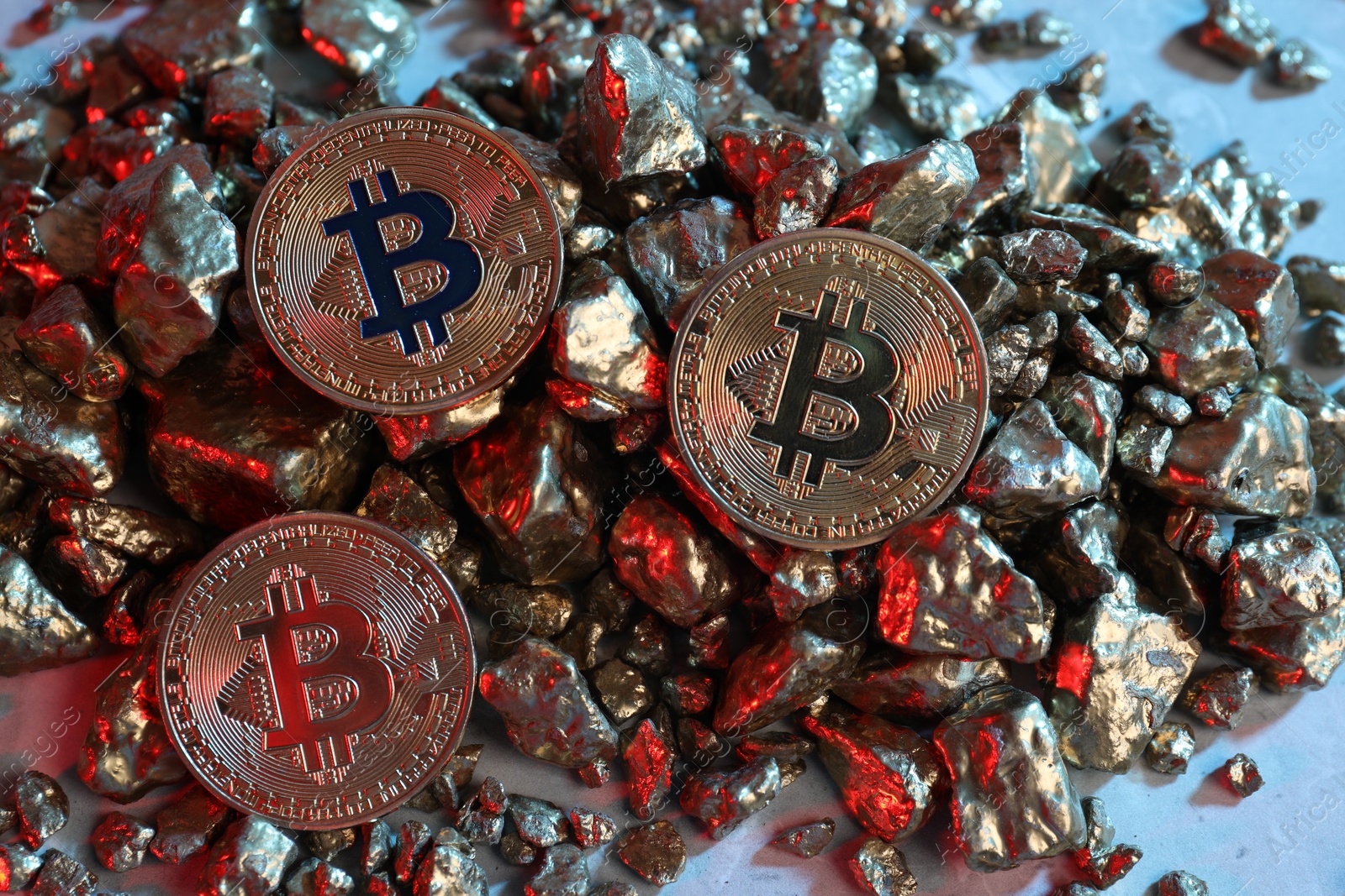Photo of Bitcoins and gold nuggets on table in red light, flat lay