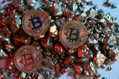 Photo of Bitcoins and gold nuggets on table in red light, flat lay