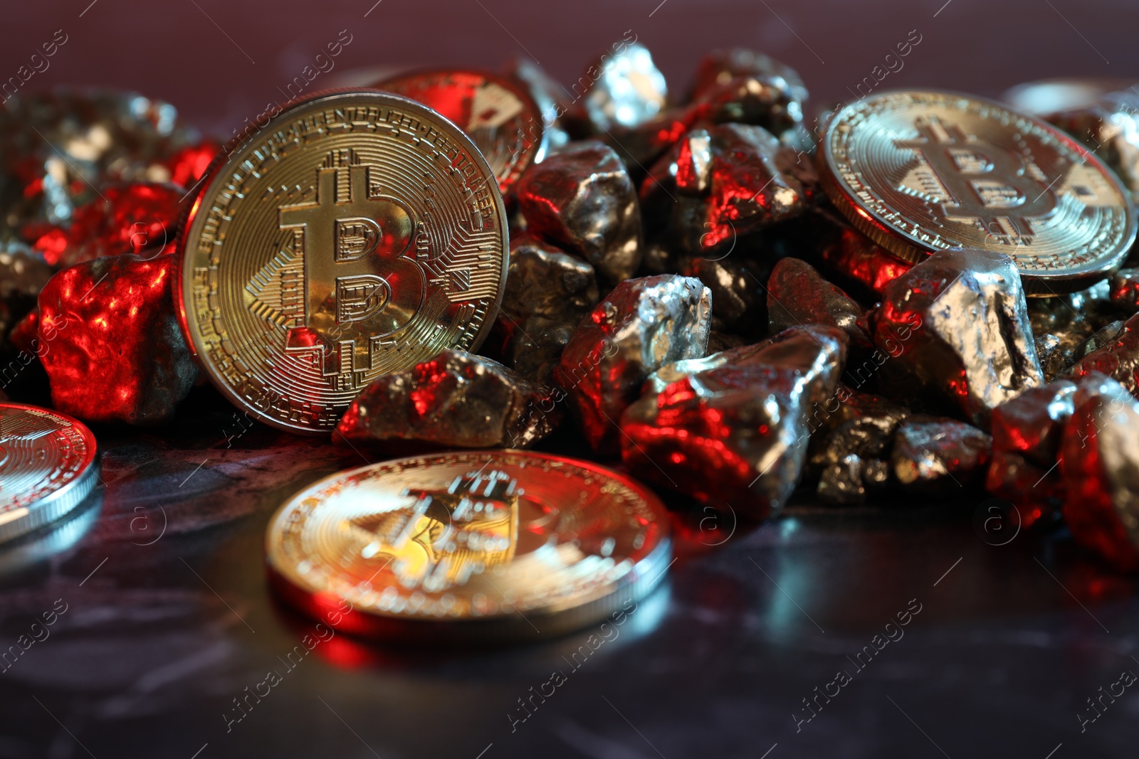 Photo of Bitcoins and gold nuggets on table in red light, closeup