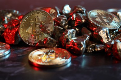 Photo of Bitcoins and gold nuggets on table in red light, closeup