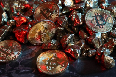 Photo of Bitcoins and gold nuggets on table in red light, closeup