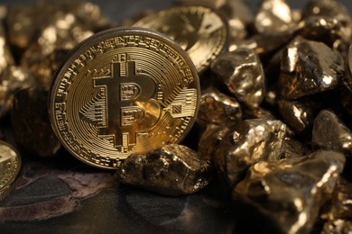 Photo of Bitcoin and gold nuggets on table, closeup