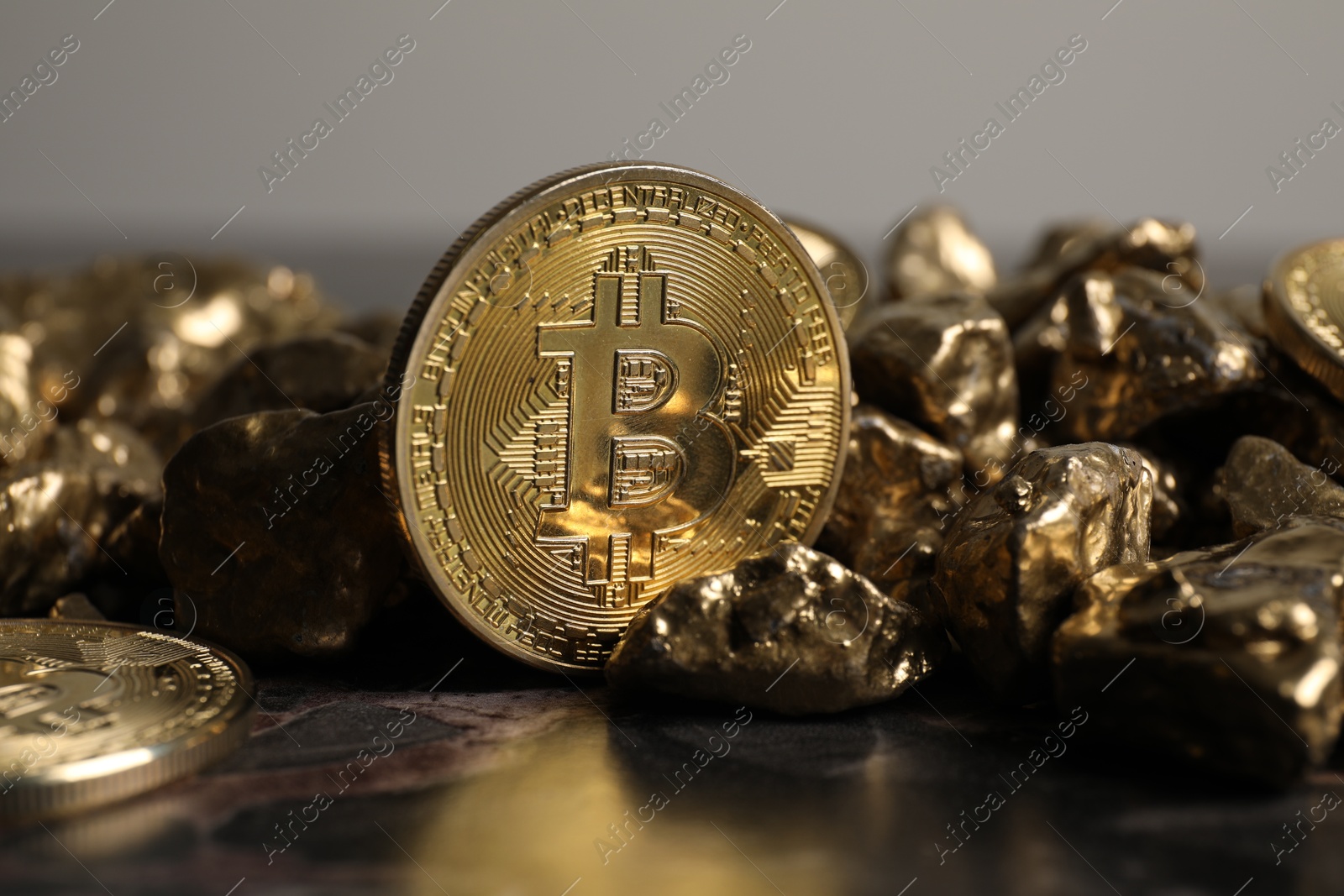 Photo of Bitcoins and gold nuggets on table, closeup