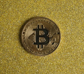 Photo of Bitcoin on golden glittery surface, top view
