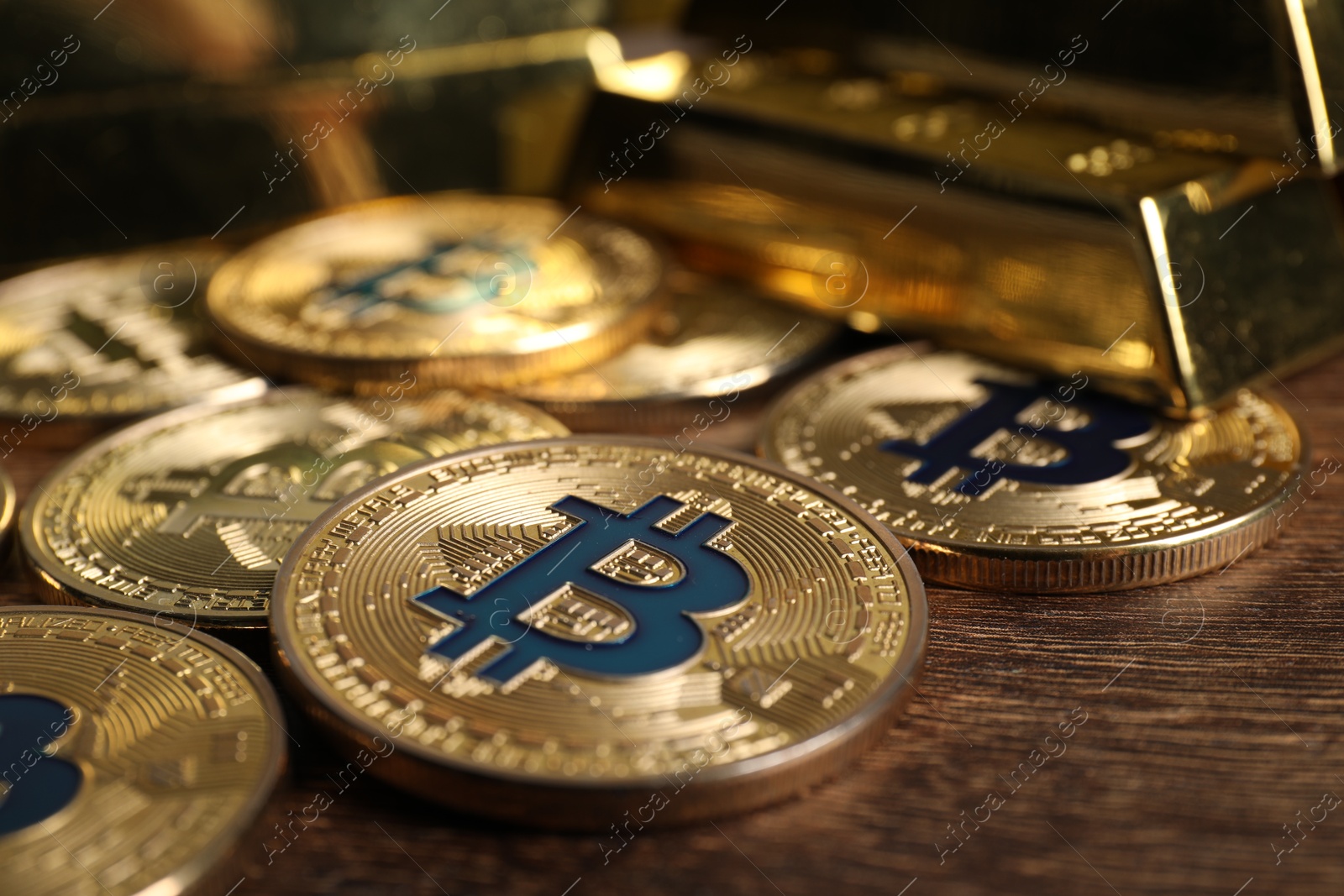 Photo of Bitcoins and gold bars on wooden table, closeup