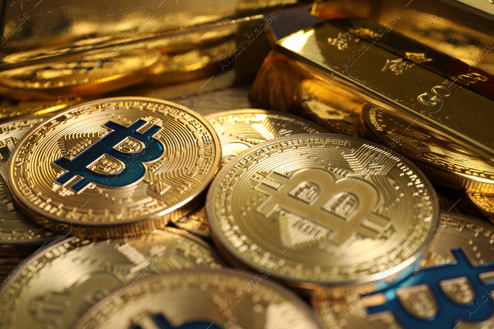 Photo of Bitcoins and gold bars on wooden table, closeup