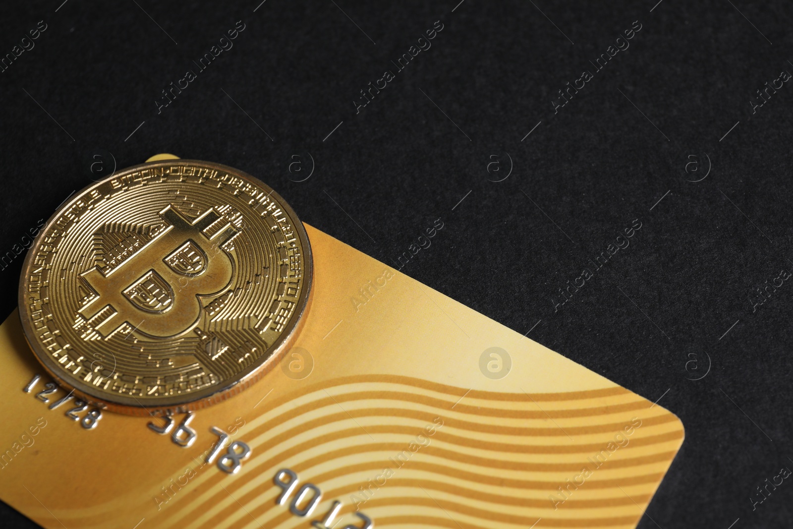 Photo of Bitcoin and plastic bank card on black background, closeup. Space for text