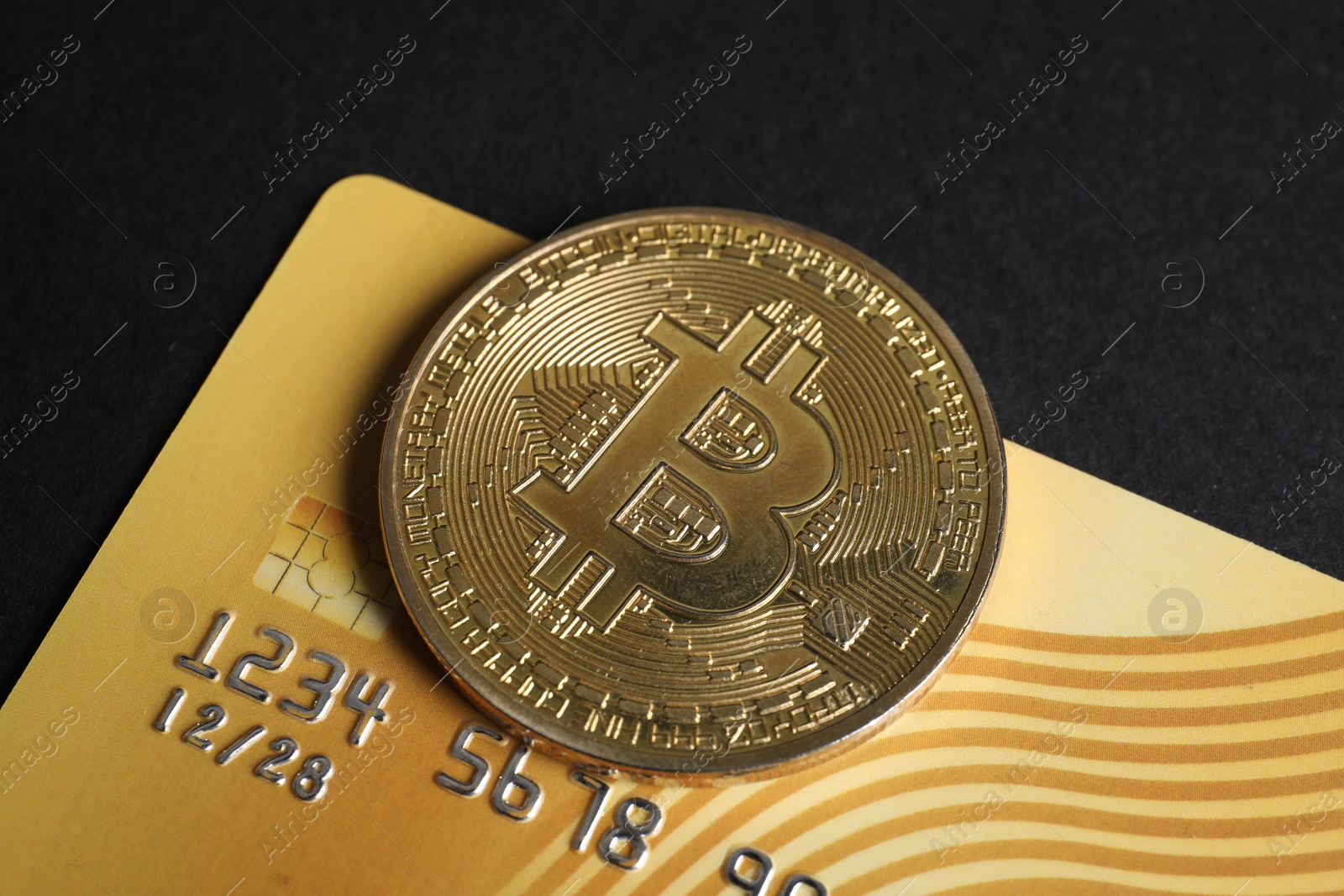 Photo of Bitcoin and plastic bank card on black background, closeup