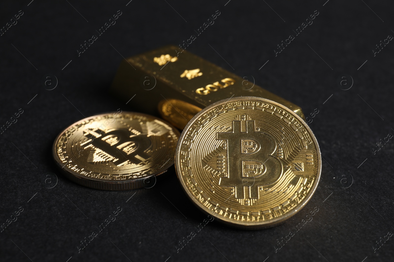 Photo of Bitcoins and gold bar on black background, closeup