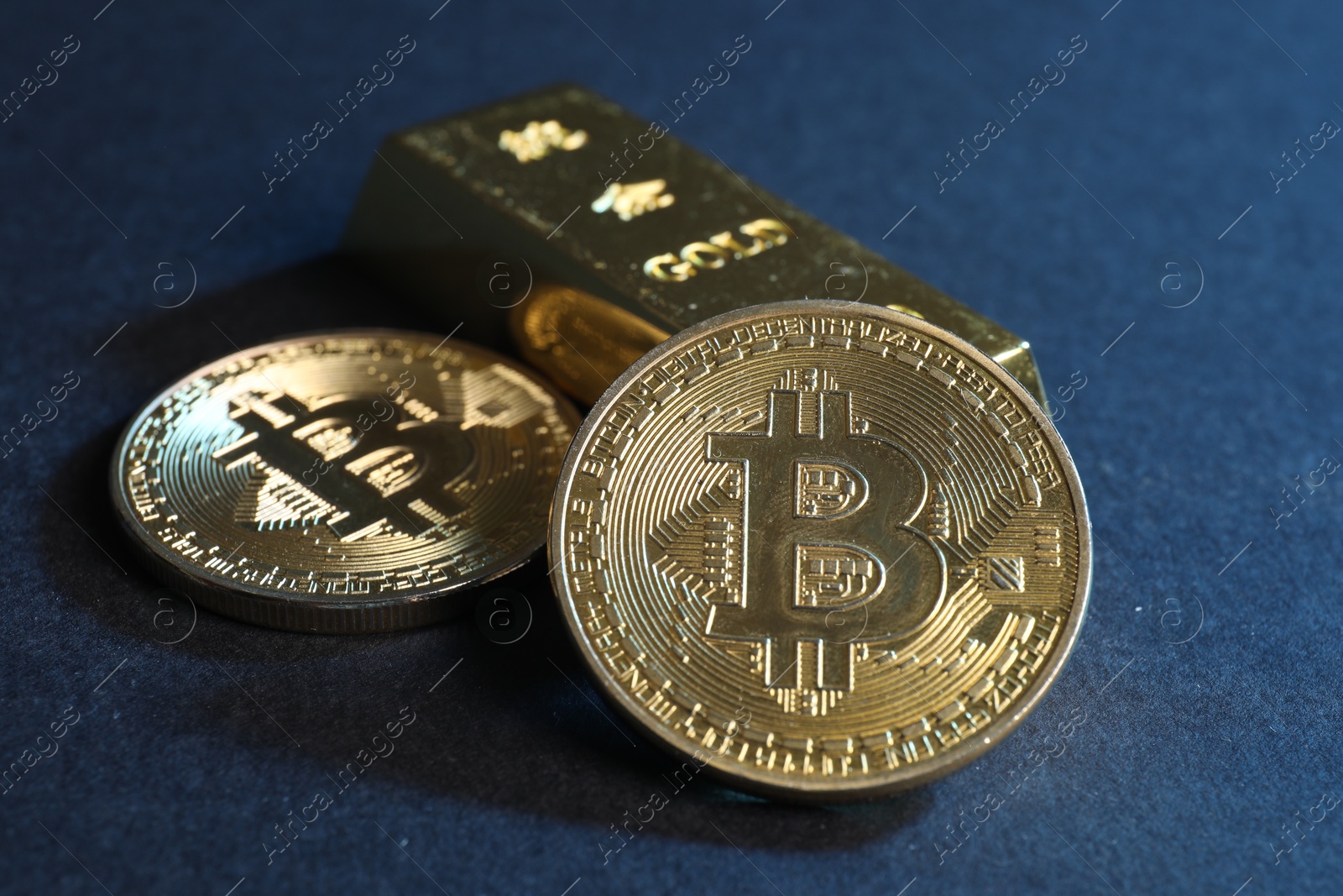 Photo of Bitcoins and gold bar on blue background, closeup